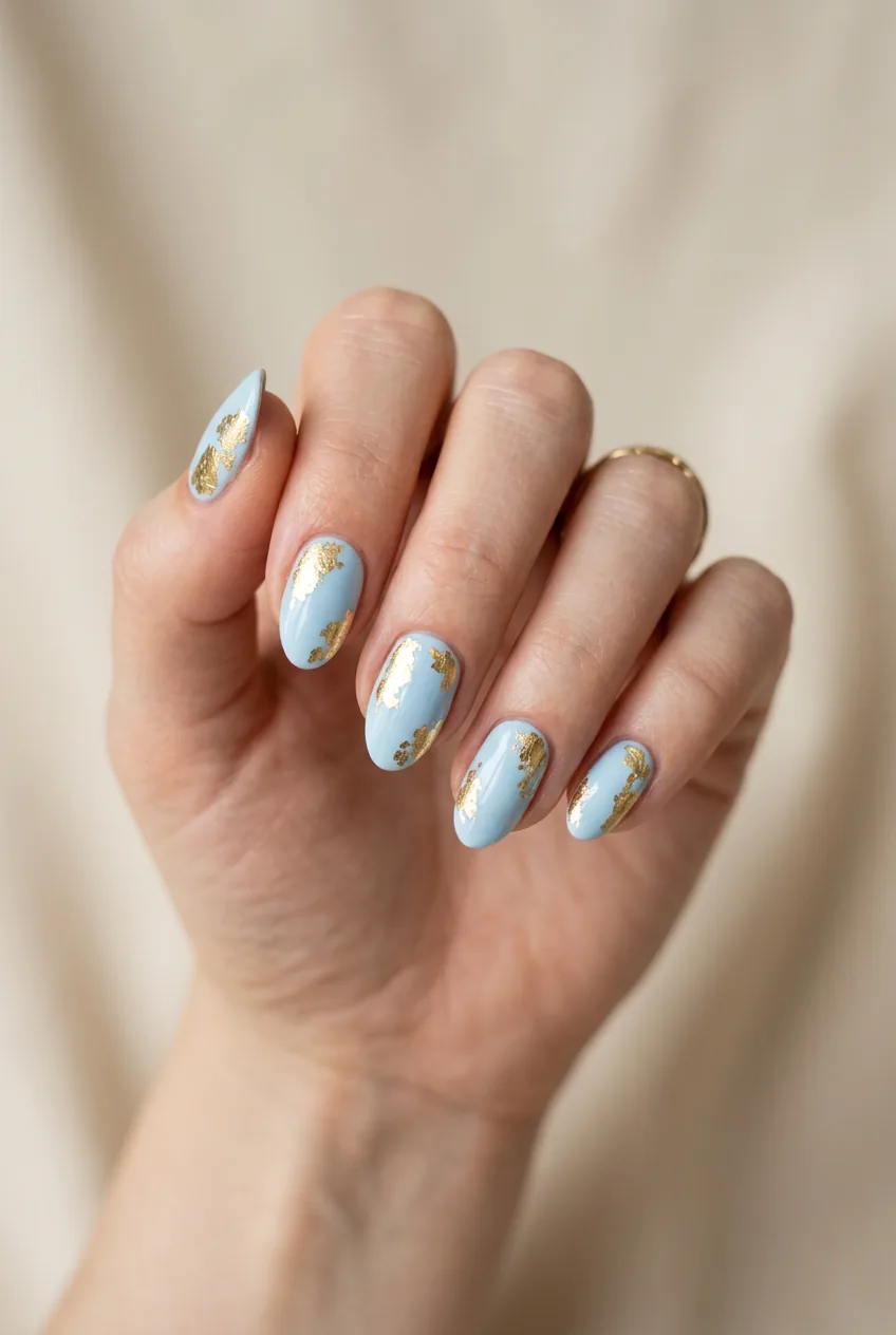 Woman's hand showing baby blue nail polish with organic gold foil accent patches
