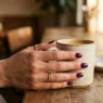 Woman's hand with deep purple manicure in soft golden hour lighting showing fresh nail polish