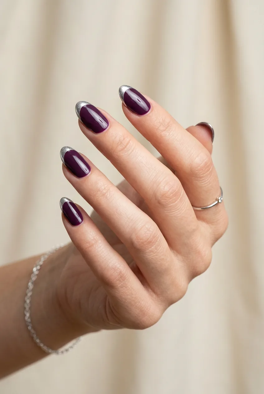 Woman's hand displaying deep purple nails with silver chrome French tips