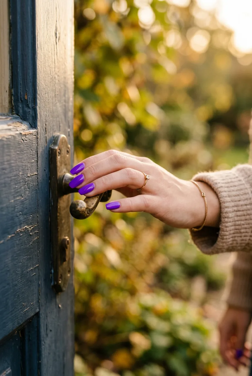 Woman's hand reaching for door handle with electric violet purple manicure visible