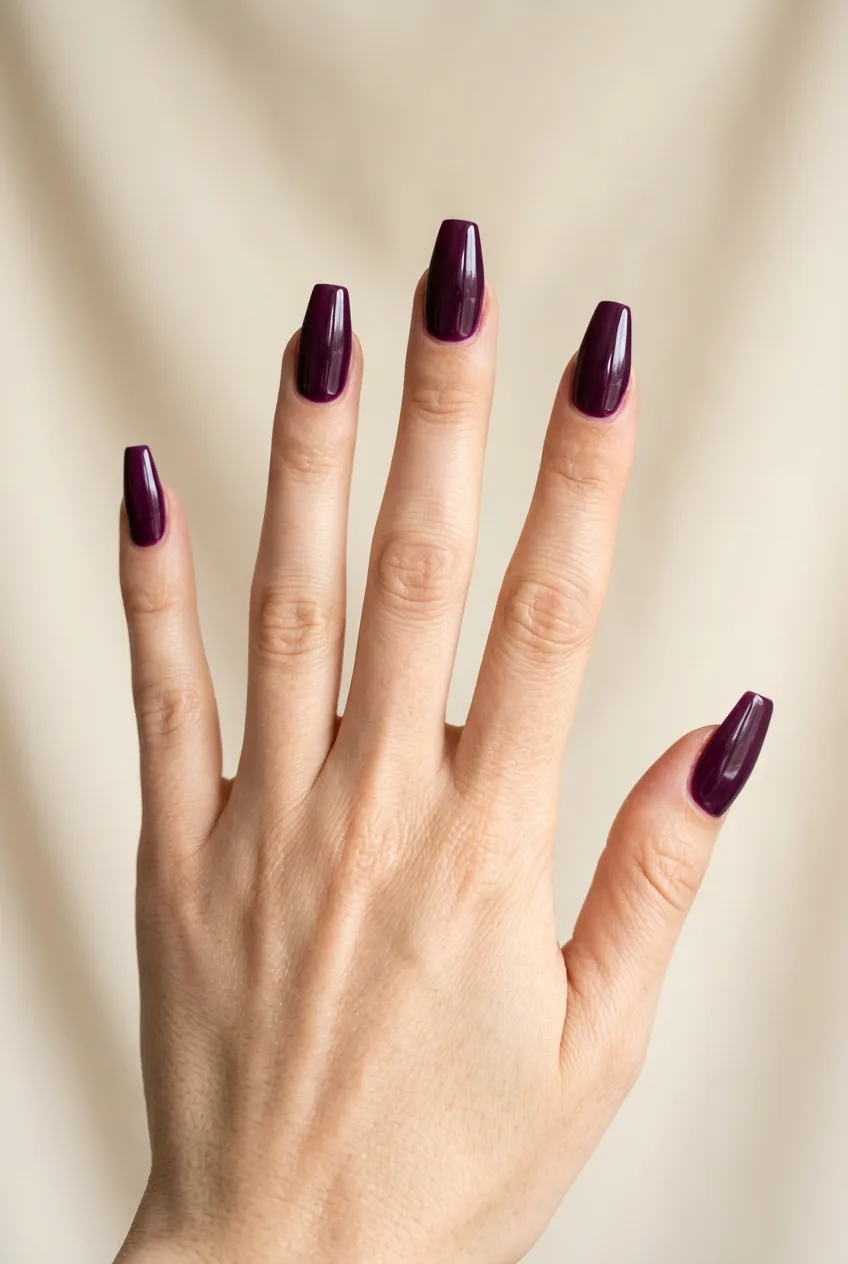 Woman's hand displaying midnight plum coffin-shaped nails with rich purple undertones