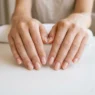 Woman's hands displaying minimalist nude manicure with sheer polish on all ten nails