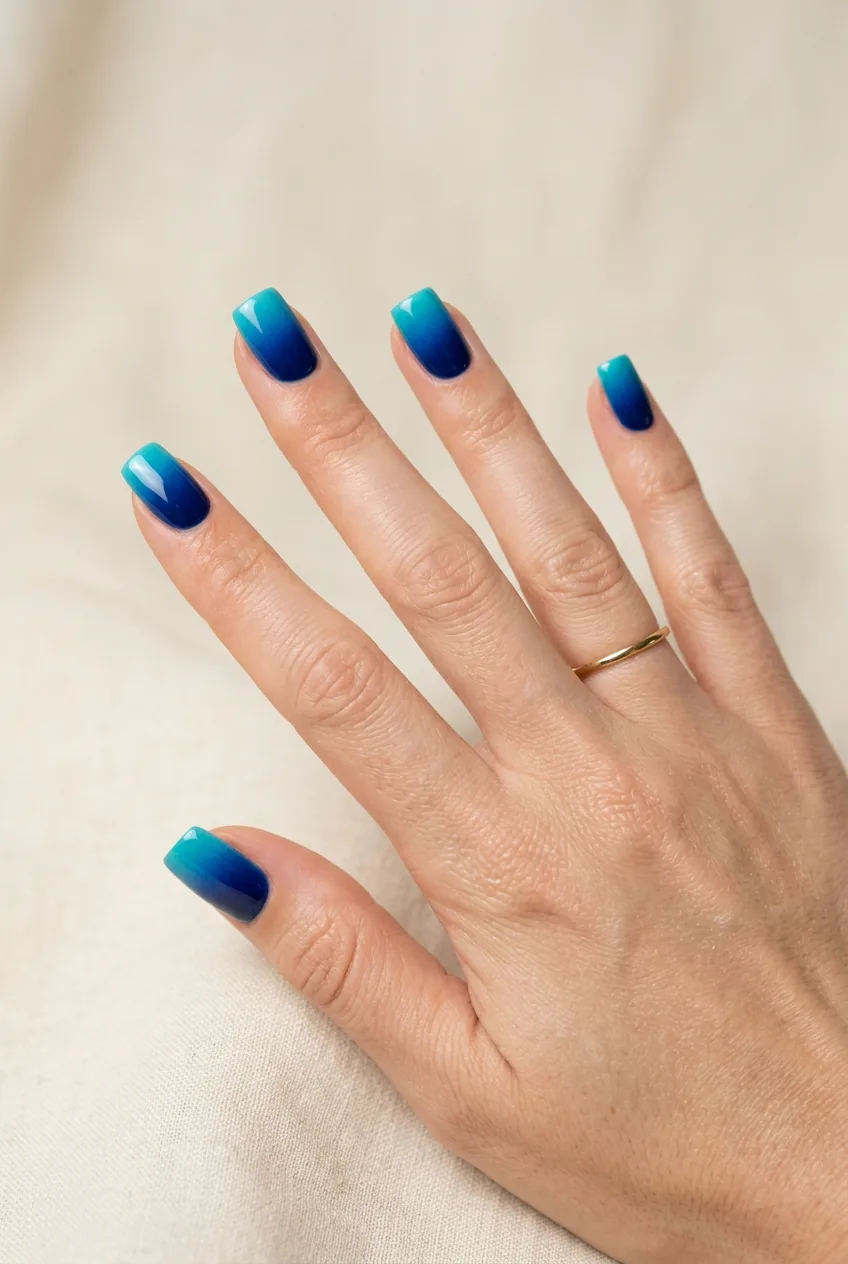 Ocean blue ombre manicure transitioning from navy at cuticle to bright turquoise at square tips