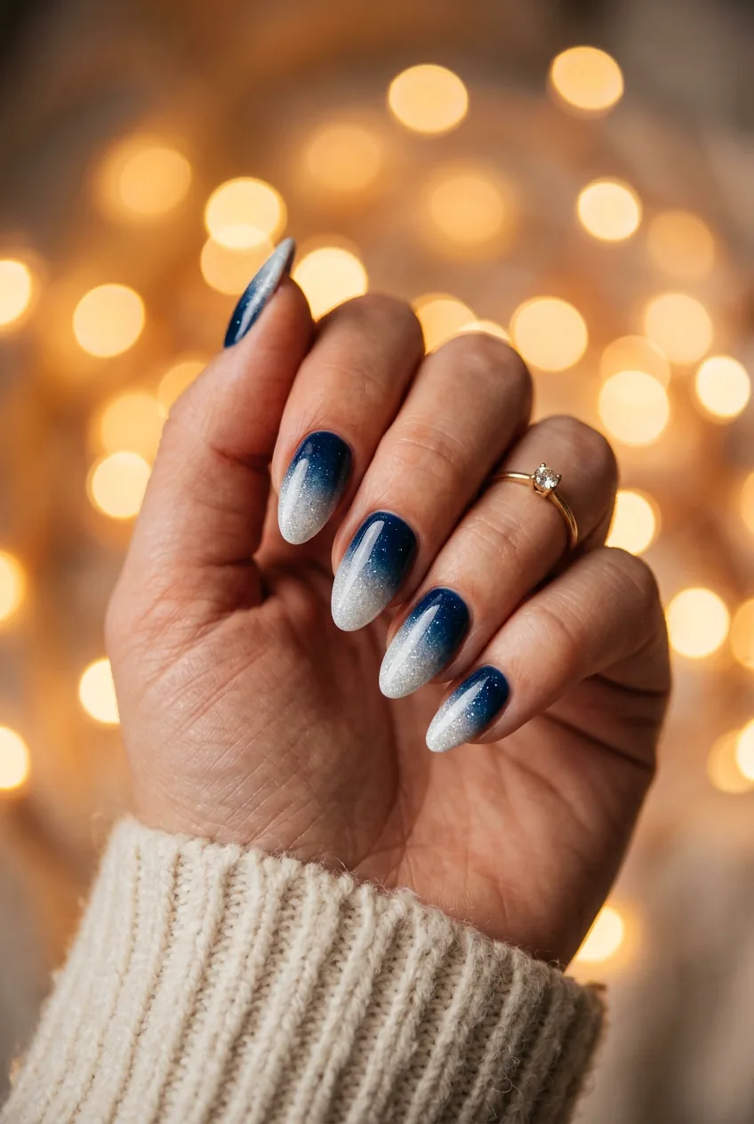 Ombré winter nails showing navy to ice white gradient fade in elegant almond shape