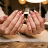Woman's hands elegantly displayed showing ten perfectly manicured nails with glossy finish under salon lighting