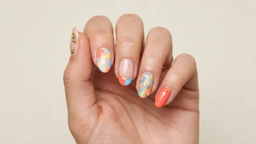 Woman's hand showing summer 2026 nail trends with mixed designs on each finger