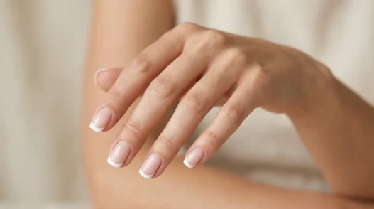 Woman's hand showing French manicure with white tips and nude pink base on short square nails