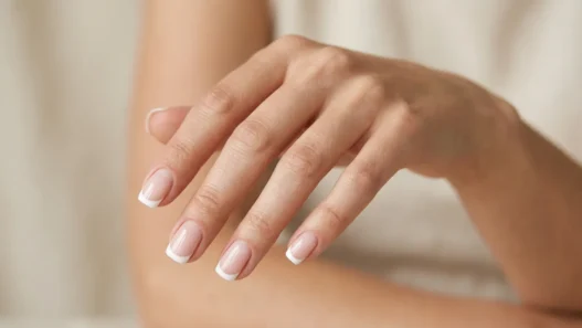 Woman's hand showing French manicure with white tips and nude pink base on short square nails