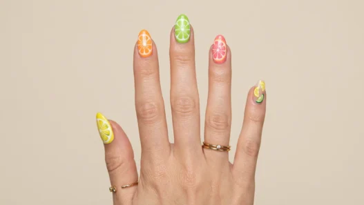 Woman's hand showing summer short nail designs with bright citrus colored tips on natural length nails