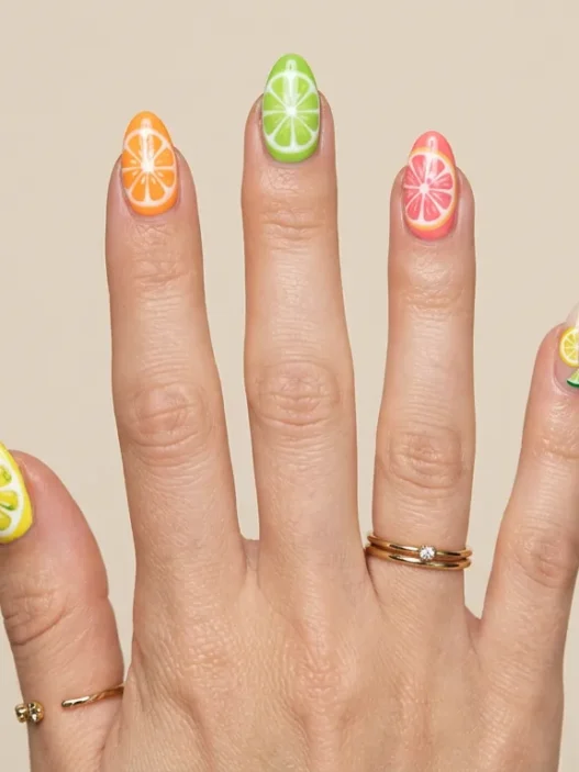 Woman's hand showing summer short nail designs with bright citrus colored tips on natural length nails