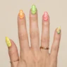Woman's hand showing summer short nail designs with bright citrus colored tips on natural length nails