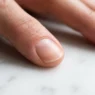 Macro close-up of a clean bare nail plate showing natural keratin surface texture under soft window light