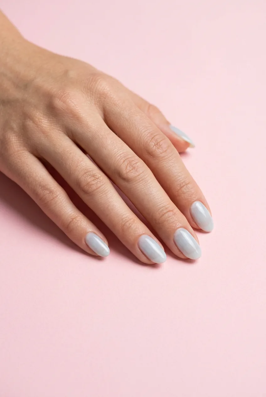 Medium oval nails in sheer icy arctic blue wash almost white and translucent on a pastel pink paper backdrop