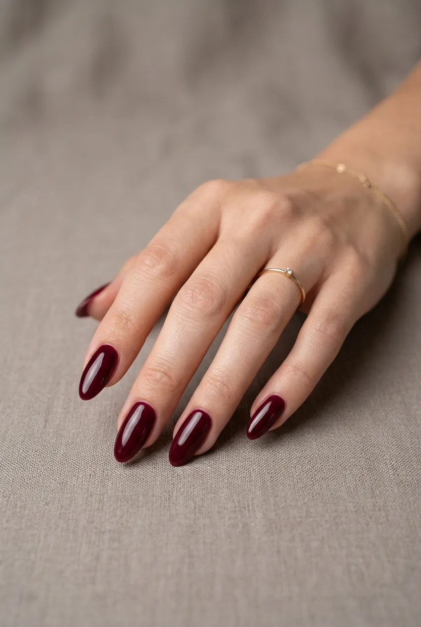 Woman's hand with longer nails painted in deep burgundy wine color with rich glossy finish