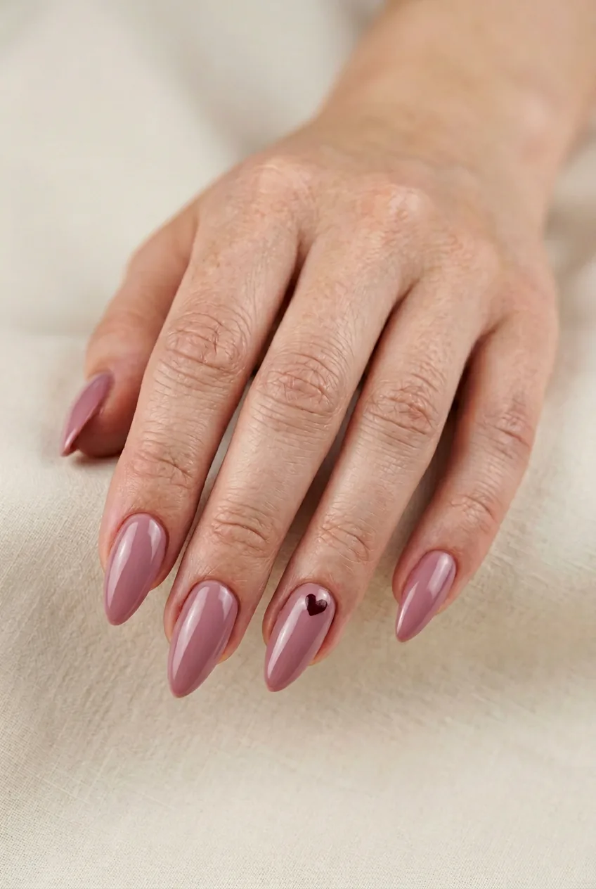 Woman's hand displaying single tiny burgundy heart accent on ring finger with dusty rose base color