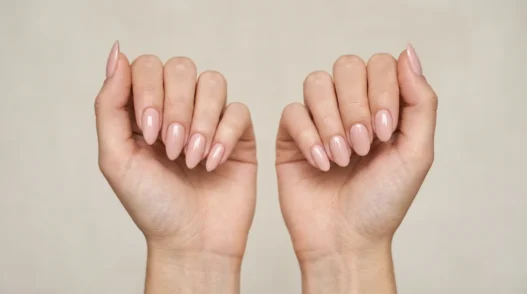 Two women's hands side by side showing almond and oval nail shape comparison in studio lighting