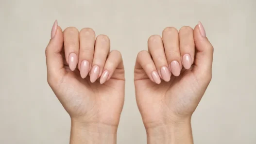 Two women's hands side by side showing almond and oval nail shape comparison in studio lighting