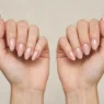 Two women's hands side by side showing almond and oval nail shape comparison in studio lighting