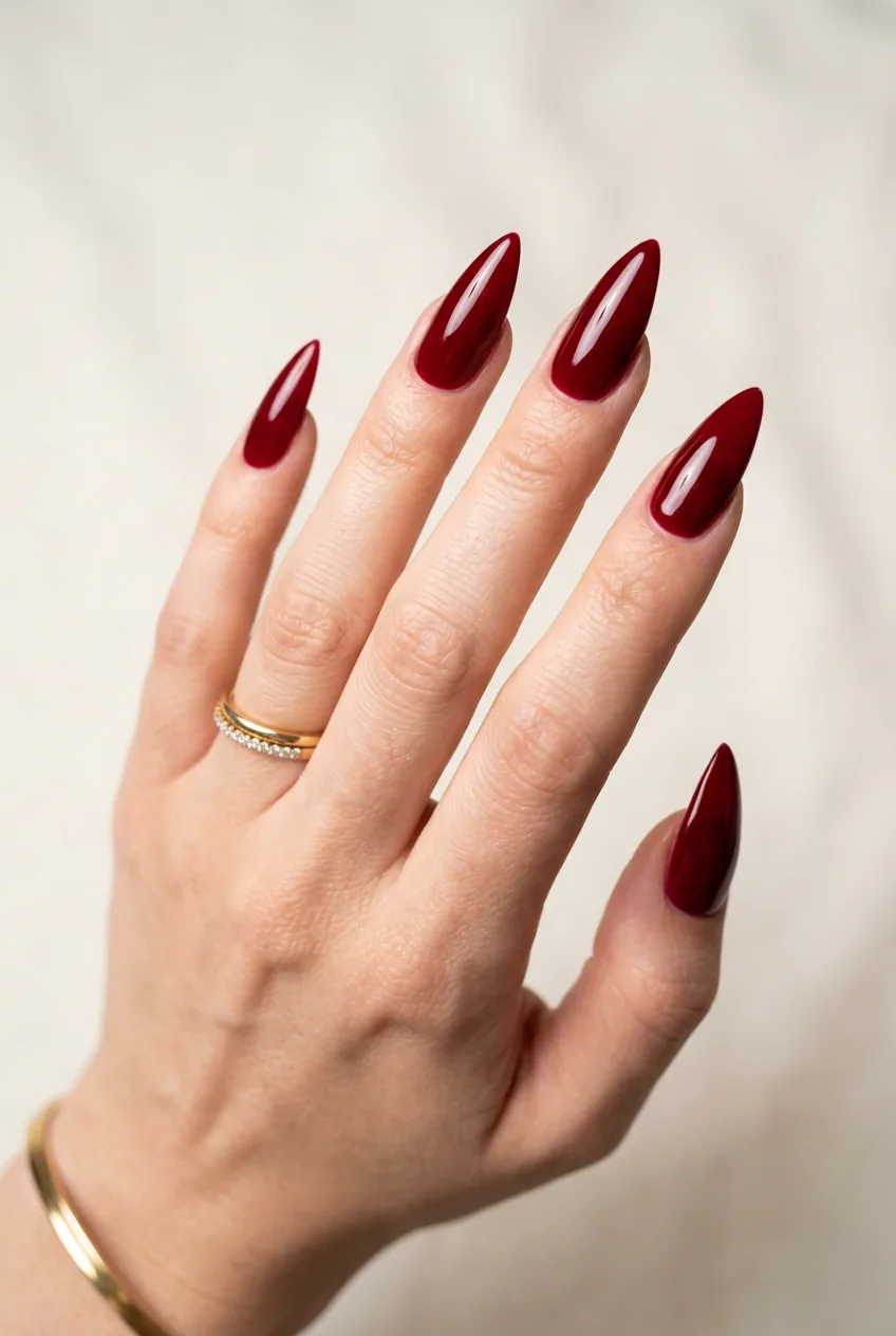 Long dramatic stiletto nails in deep blood-red crimson with mirror-shine high-gloss top coat