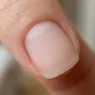 Close-up of a freshly buffed nail surface showing uniform matte texture after filing prep under warm light
