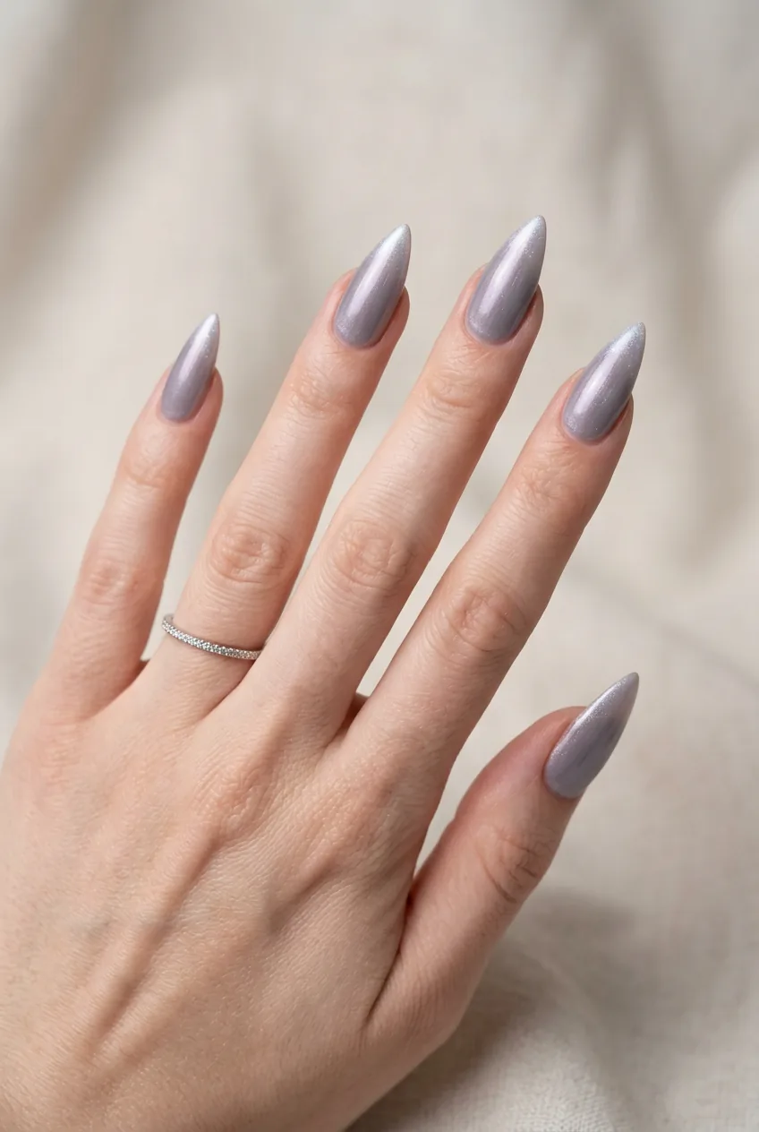 Five stiletto nails in dusty grey-lavender with pearl shimmer frost visible at pointed tips