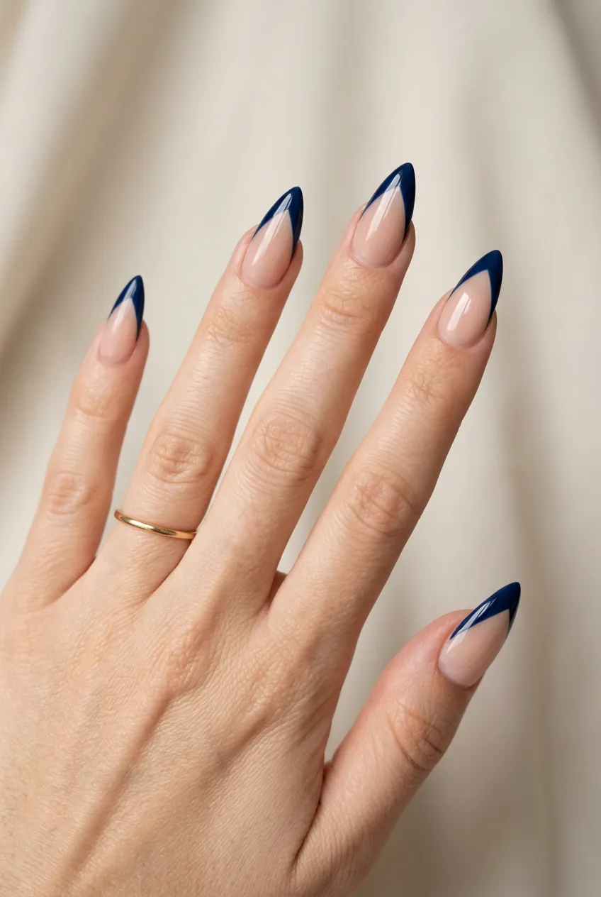 Five stiletto nails with deep navy colored French tip following the pointed V shape of each nail