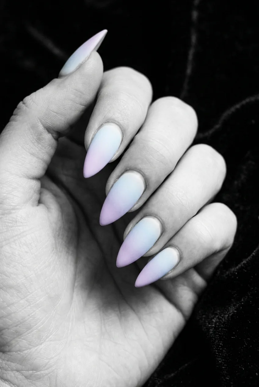 Stiletto nails in a baby blue to soft lilac pastel gradient ombre on dark matte black background