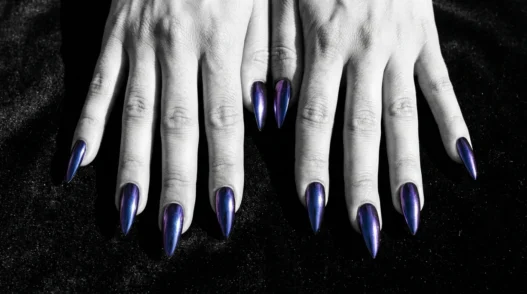 All ten stiletto nails fanned out showing deep midnight chrome finish that shifts cobalt to purple on dark velvet surface