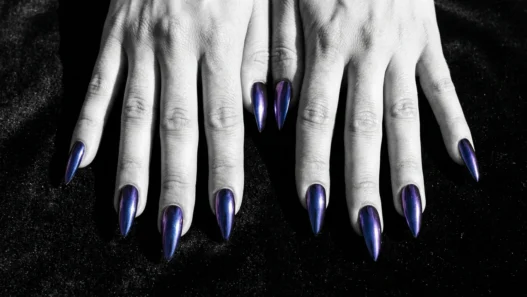 All ten stiletto nails fanned out showing deep midnight chrome finish that shifts cobalt to purple on dark velvet surface