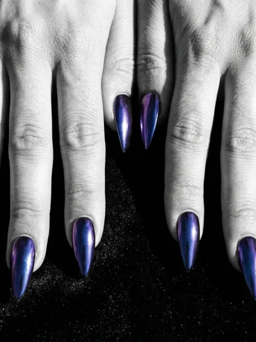All ten stiletto nails fanned out showing deep midnight chrome finish that shifts cobalt to purple on dark velvet surface