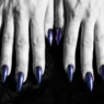 All ten stiletto nails fanned out showing deep midnight chrome finish that shifts cobalt to purple on dark velvet surface